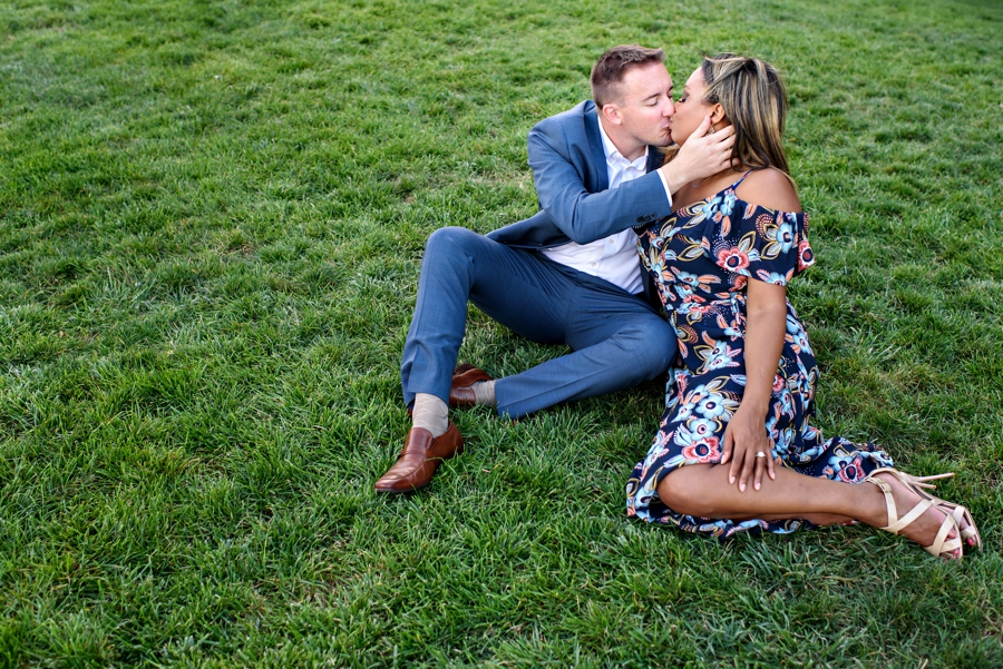 A man kisses his bride to be in the grass along the river in Hoboken, NJ.